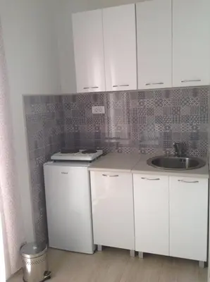 a small kitchen with white cabinets and a sink at Dalukos Apartmani in Sutomore