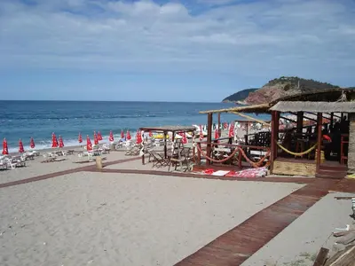 a beach with chairs and umbrellas and the ocean at Dalukos Apartmani in Sutomore