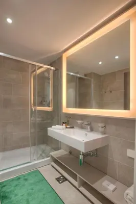 a bathroom with a sink and a shower and a mirror at Fontana Hotel & Gastronomy in Budva