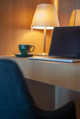 a laptop on a desk with a cup and a lamp at Fontana Hotel & Gastronomy in Budva