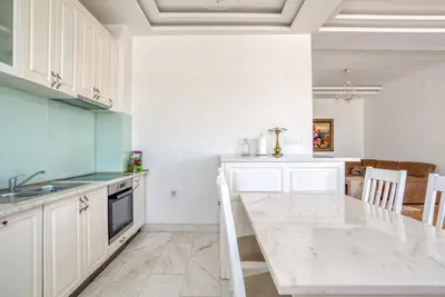 a kitchen with white cabinets and a marble counter top at Apartman Marko in Podgorica