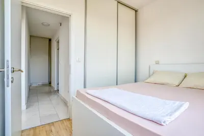 a white bedroom with a pink bed and a corridor at Apartman Marko in Podgorica