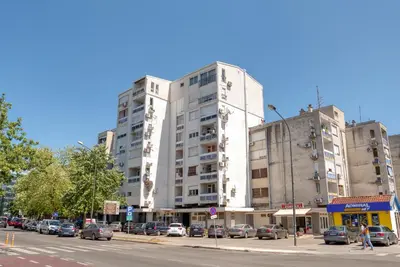a tall white building with cars parked in front of it at Apartman Marko in Podgorica