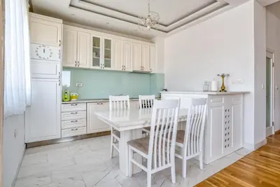 a kitchen with white cabinets and a white table and chairs at Apartman Marko in Podgorica