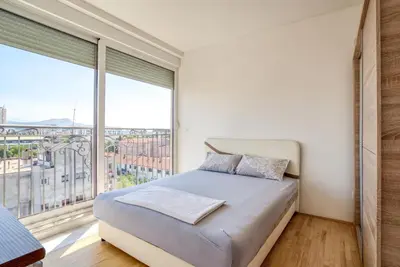 a bedroom with a bed and a large window at Apartman Marko in Podgorica