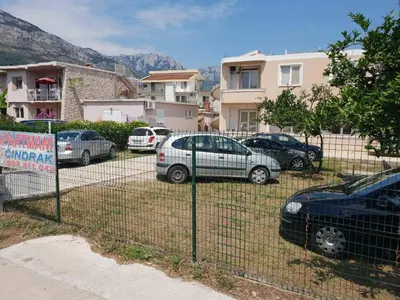 a fence with cars parked in a parking lot at Apartments Cindrak in Bar