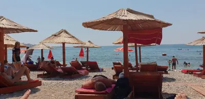 a group of people laying on a beach with umbrellas at Apartments Cindrak in Bar