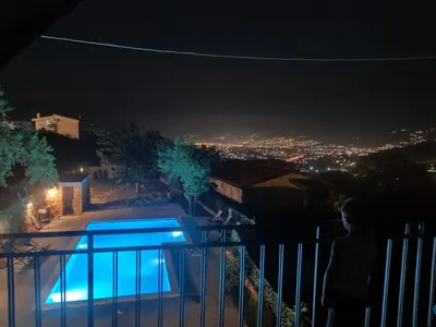 a person standing on a balcony looking at a city at night at Stone Villa UK - Dobra Voda in Bar