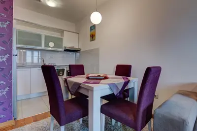 a dining room with a table and purple chairs at Eureka Apartment in Podgorica