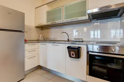 a kitchen with white cabinets and a sink and a refrigerator at Eureka Apartment in Podgorica