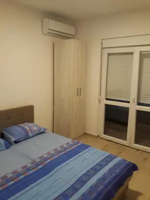 a bedroom with a bed and a closet and a window at Apartmani Miljevci in Sutomore