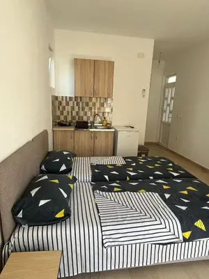 two beds in a small room with a kitchen at Apartmani Miljevci in Sutomore