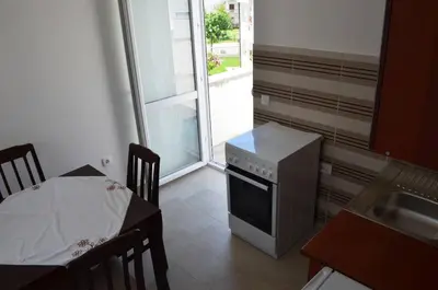 a kitchen with a stove and a table and a window at Apartmani Miljevci in Sutomore
