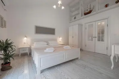 a white bedroom with a white bed and a table at Marinero Apartments in Budva