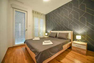 a bedroom with a large bed and a large wall at Apartment Bono Lux City Kvart in Podgorica