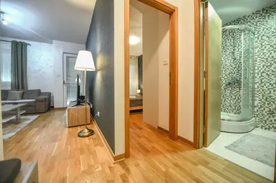 a hallway with a living room with a couch and a lamp at Apartment Bono Lux City Kvart in Podgorica