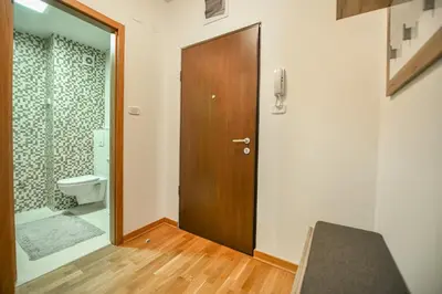 a bathroom with a toilet and a wooden door at Apartment Bono Lux City Kvart in Podgorica