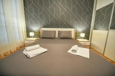a bedroom with a large bed with towels on it at Apartment Bono Lux City Kvart in Podgorica