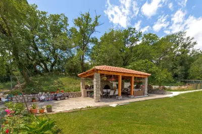 a gazebo with a fireplace in a garden at Apartments Pelle in Tivat