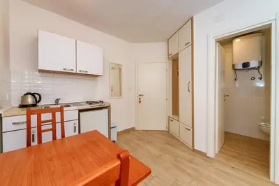 a kitchen with white cabinets and a wooden table at Gregovic Family Apartments in Petrovac na Moru