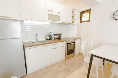 a kitchen with white cabinets and a table with chairs at Gregovic Family Apartments in Petrovac na Moru