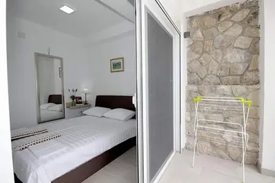 a bedroom with a bed and a stone wall at Apartmani Kasija in Dobra Voda