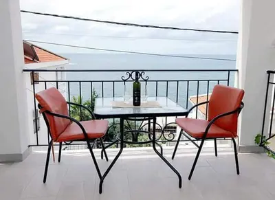 a table and chairs on a balcony with a view of the ocean at Apartmani Kasija in Dobra Voda