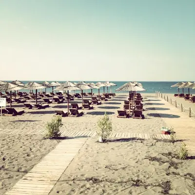 a beach with chairs and umbrellas and the ocean at Apartments Dalila in Ulcinj