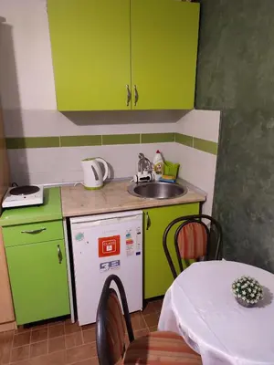 a kitchen with green cabinets and a sink and a table at Apartments Blago Sutomore in Sutomore