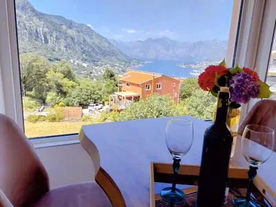 a table with two wine glasses and a vase with flowers at Apartment Dora in Kotor