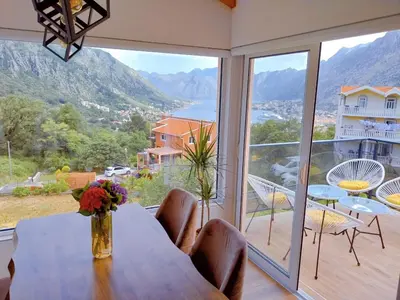a dining room with a table and a large window at Apartment Dora in Kotor