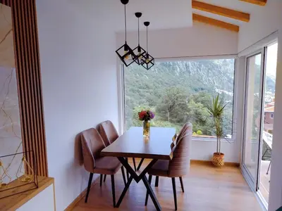 a dining room with a table and chairs and a large window at Apartment Dora in Kotor