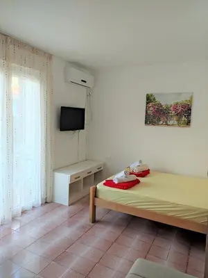 a white room with a bed and a television at Guest House Lotos in Becici
