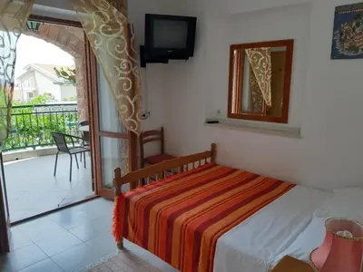 a bedroom with a bed and a balcony with a television at Zoro Apartments in Sveti Stefan