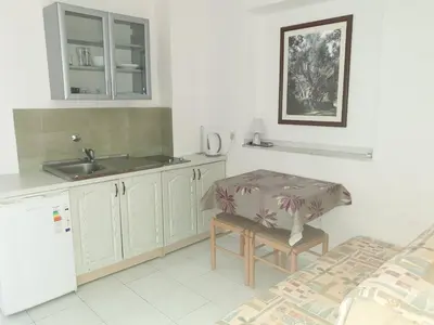 a kitchen with white cabinets and a table and a sink at Zoro Apartments in Sveti Stefan
