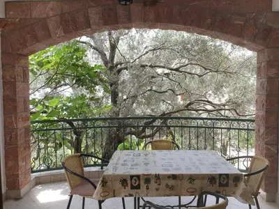 a table and chairs on a balcony with a tree at Zoro Apartments in Sveti Stefan