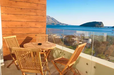 a table and chairs on a balcony with a view of the ocean at Montesun Apartments in Budva