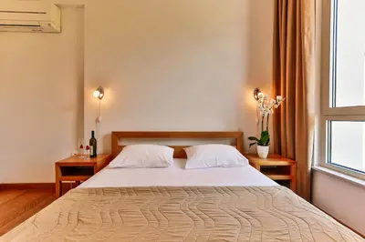 a bedroom with a bed with white sheets and a window at Montesun Apartments in Budva