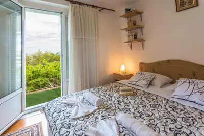 a bedroom with a bed and a large window at Apartmani Steni in Sveti Stefan