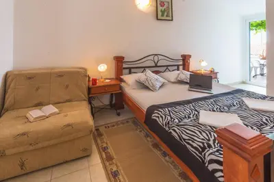 a bedroom with a bed and a chair with a laptop on it at Apartmani Steni in Sveti Stefan