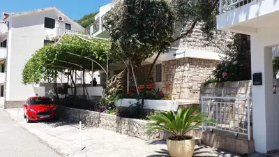 a red car parked in front of a house at Apartmani Steni in Sveti Stefan