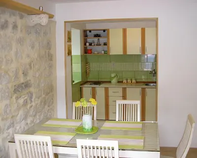 a kitchen with a table and chairs and a kitchen with a counter at Apartments Vojvoda in Kotor
