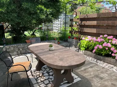 a wooden table and chairs in a garden with flowers at Apartments Vojvoda in Kotor