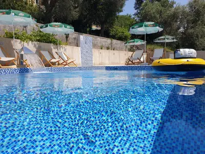 a swimming pool with chairs and umbrellas and a swimming pool at GREJM Lux Family Apartments in Petrovac na Moru