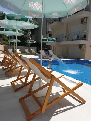 a row of lounge chairs and umbrellas next to a swimming pool at GREJM Lux Family Apartments in Petrovac na Moru