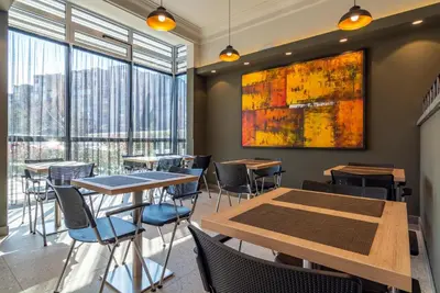 a restaurant with tables and chairs and a large window at Hotel Resurs in Podgorica