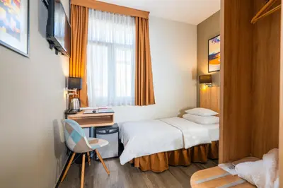 a hotel room with a bed and a desk and a window at Hotel Resurs in Podgorica