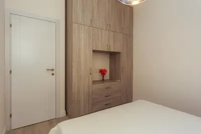 a bedroom with a cabinet with a red flower in it at Belvedere Apartments in Petrovac na Moru