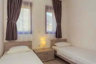 two beds in a room with two windows at Belvedere Apartments in Petrovac na Moru