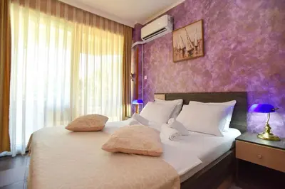 a bedroom with a large bed with a purple wall at Apartment Golden Lavender in Budva